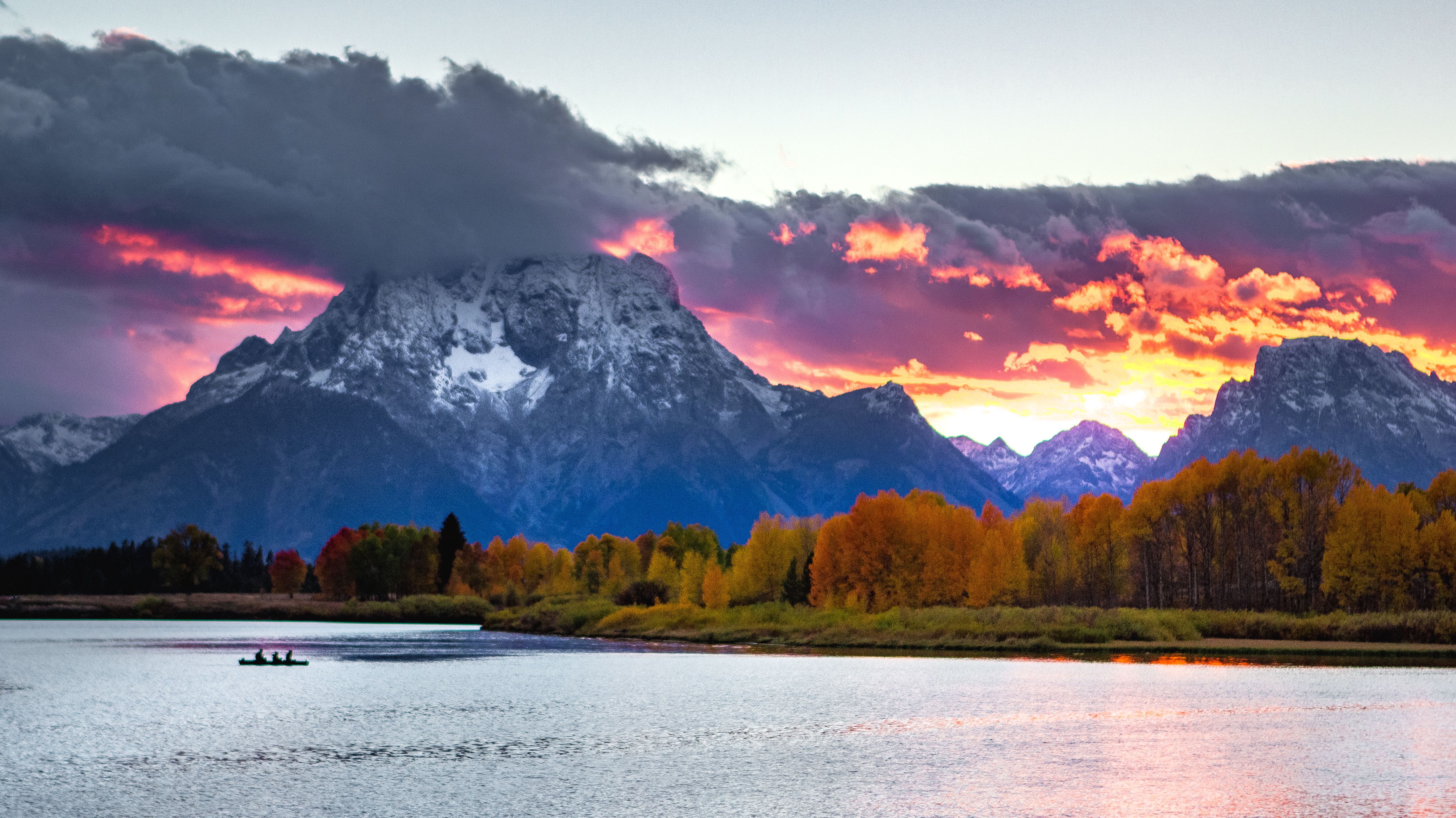 Mount Moran at sunset over Oxbow Bend, with autumn trees and a canoe on the Snake River