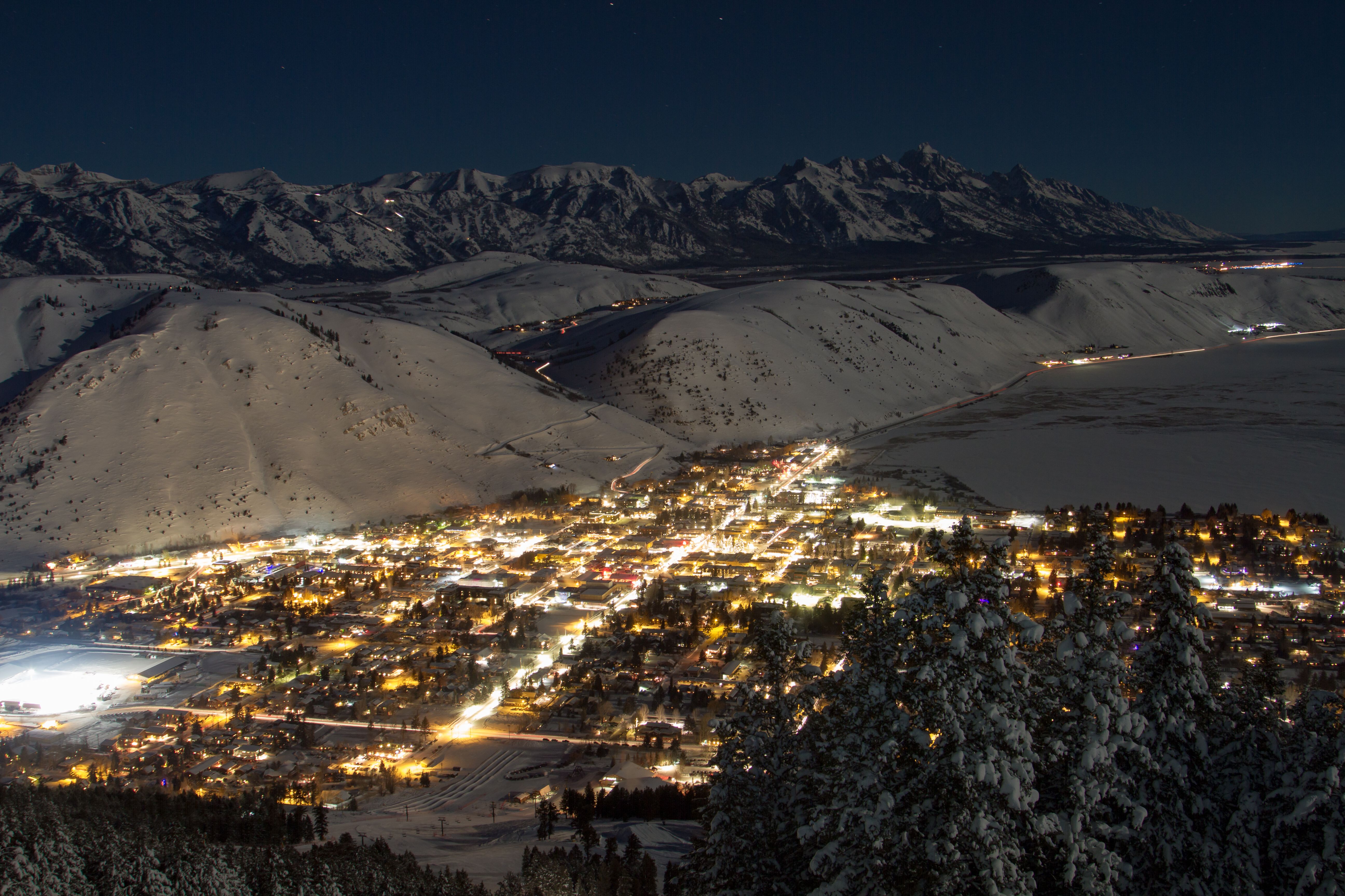 The town of Jackson glowing at night beneath the snow-covered Teton range